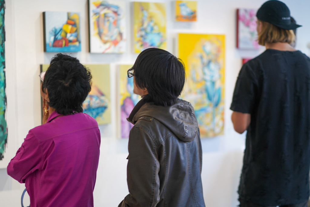 Photograph of three people viewing artwork during the "Reflect.Renew.Rebirth" duo exhibition opening reception at Voss Gallery in San Francisco, July 21, 2023.