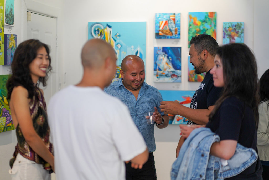 Photograph of people talking to the artist during the "Reflect.Renew.Rebirth" duo exhibition opening reception at Voss Gallery in San Francisco, July 21, 2023.