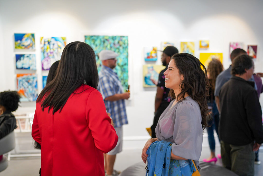 Photograph of women discussing during the "Reflect.Renew.Rebirth" duo exhibition opening reception at Voss Gallery in San Francisco, July 21, 2023.