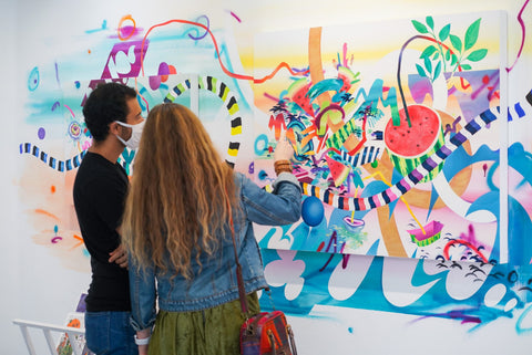 Photograph of two people talking in front of paintings during Joshua Nissen King's "Fruit of Another"solo exhibition Meet the Artist Event at Voss Gallery, San Francisco, September 12, 2020.