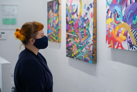 Photograph of a woman wearing face mask and looking at a painting during Joshua Nissen King's "Fruit of Another"solo exhibition Meet the Artist Event at Voss Gallery, San Francisco, September 12, 2020.