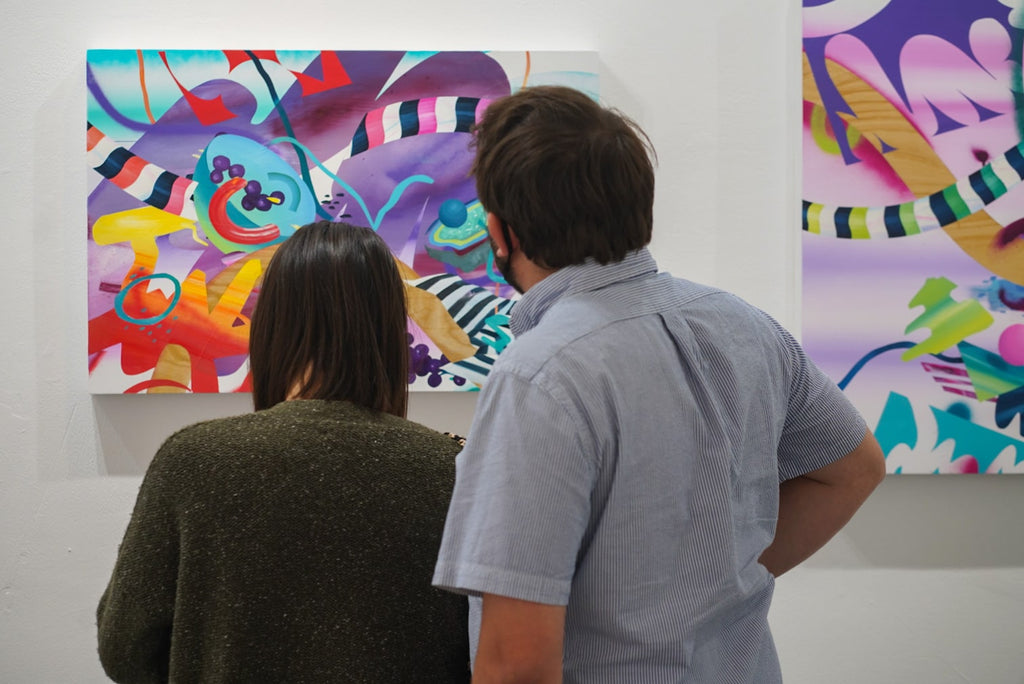 Photograph of a couple looking at paintings during Joshua Nissen King's "Fruit of Another"solo exhibition Meet the Artist Event at Voss Gallery, San Francisco, September 12, 2020.