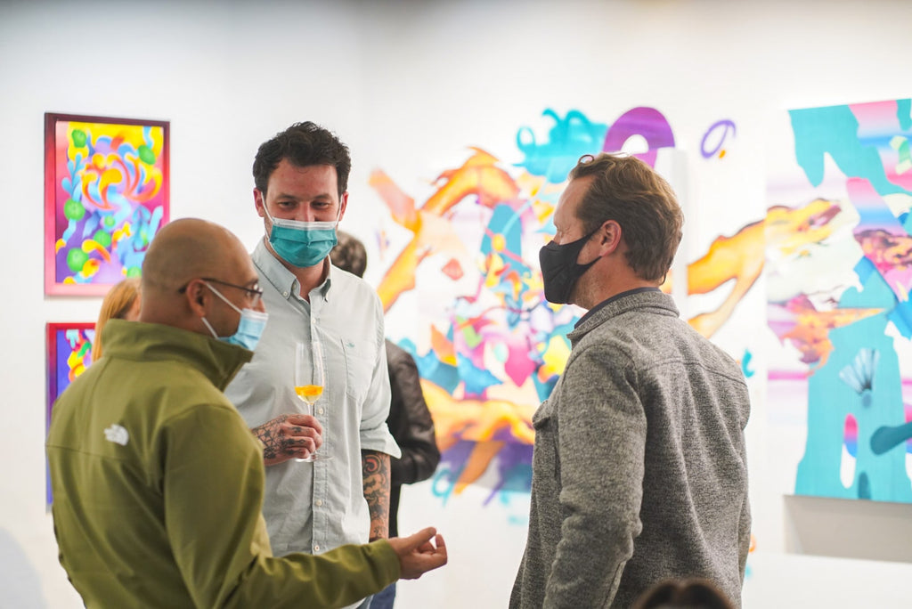 Photograph of artist talking to guests during Jennifer Banzaca & Joshua Nissen King's "Mirage" duo exhibition Opening Reception at Voss Gallery, October 22, 2021.