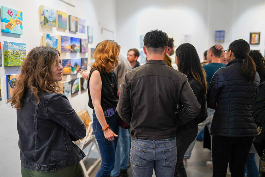 Photograph of visitors talking and viewing artwork during the Opening Reception of the Postcards from Paradise Juried Group Exhibition at Voss Gallery in San Francisco, May 26, 2023.