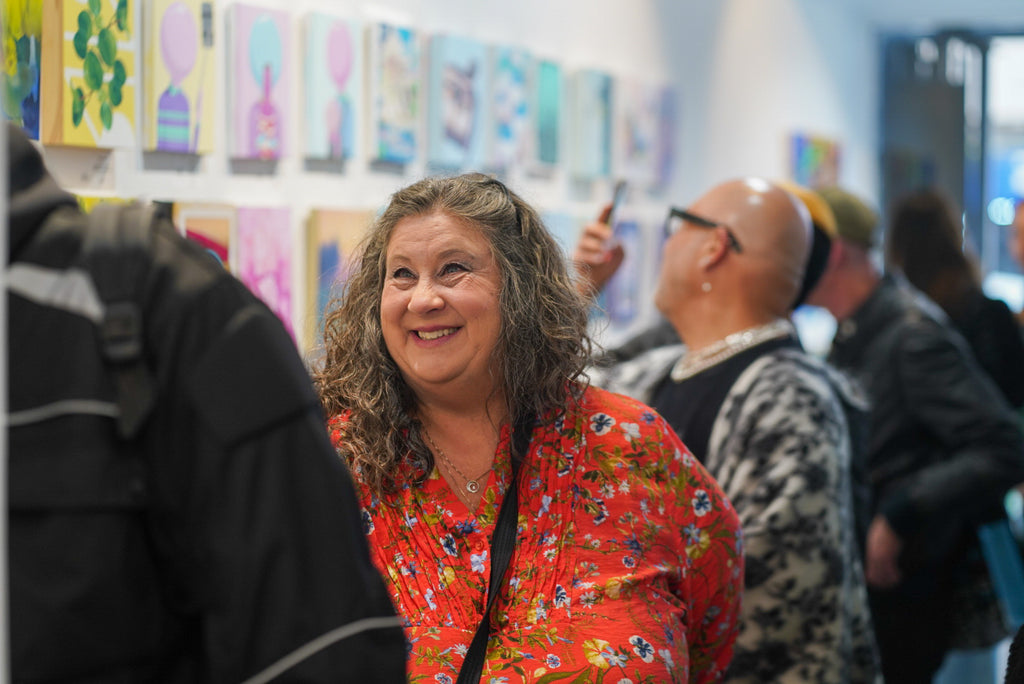 Photograph of woman smiling during the Opening Reception of the Postcards from Paradise Juried Group Exhibition at Voss Gallery in San Francisco, May 26, 2023.