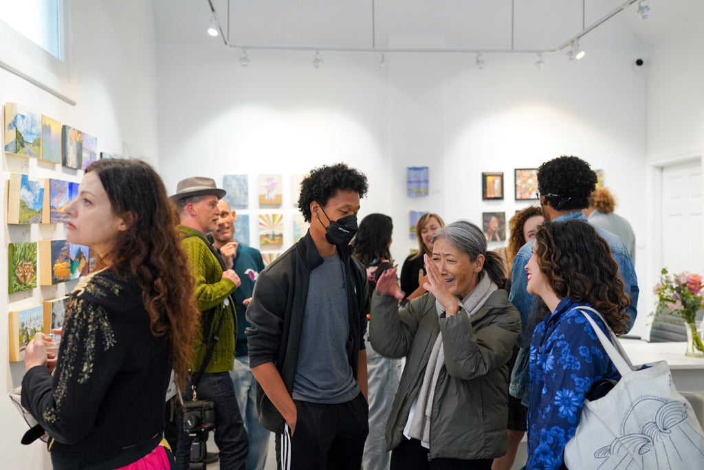 Photograph of gallery visitors talking during the Postcards from Paradise Juried Group Exhibition Opening Reception at Voss Gallery in San Francisco, May 26, 2023.