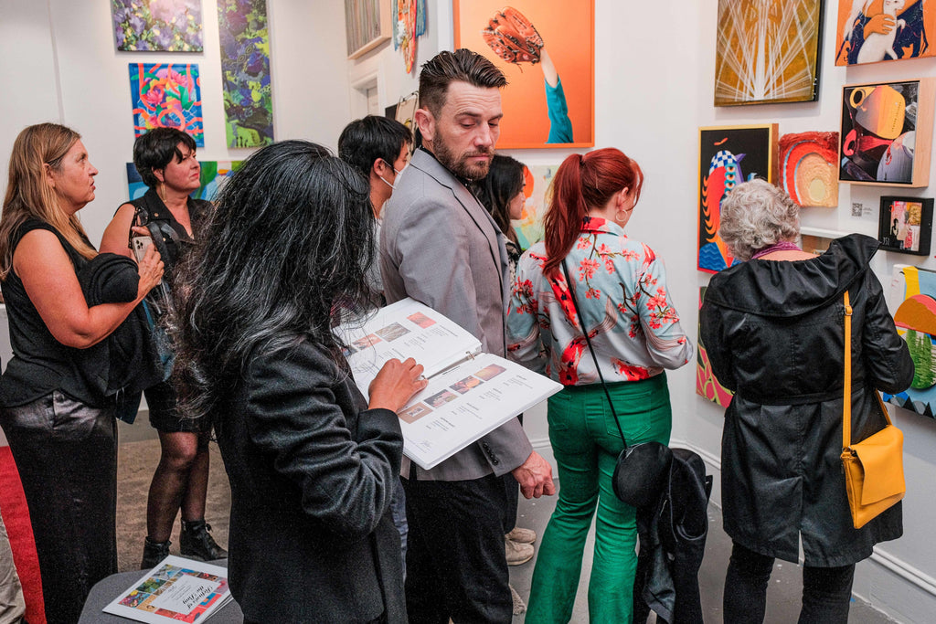 Photograph of group of people viewing artwork on the wall during "Refusés of the Bay" Group Exhibition Opening Reception at Voss Gallery, San Francisco, September 29, 2023.