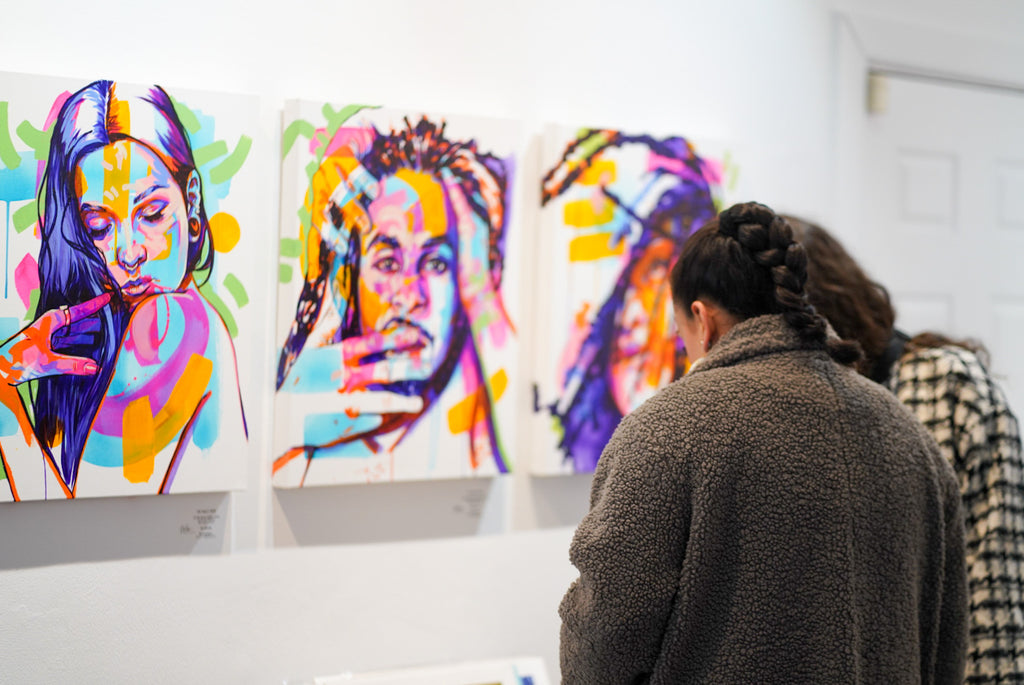 Photograph of two people looking at artwork during the opening reception of The Tracy Piper's "All the Feels" solo exhibition at Voss Gallery, San Francisco, August 25, 2023.