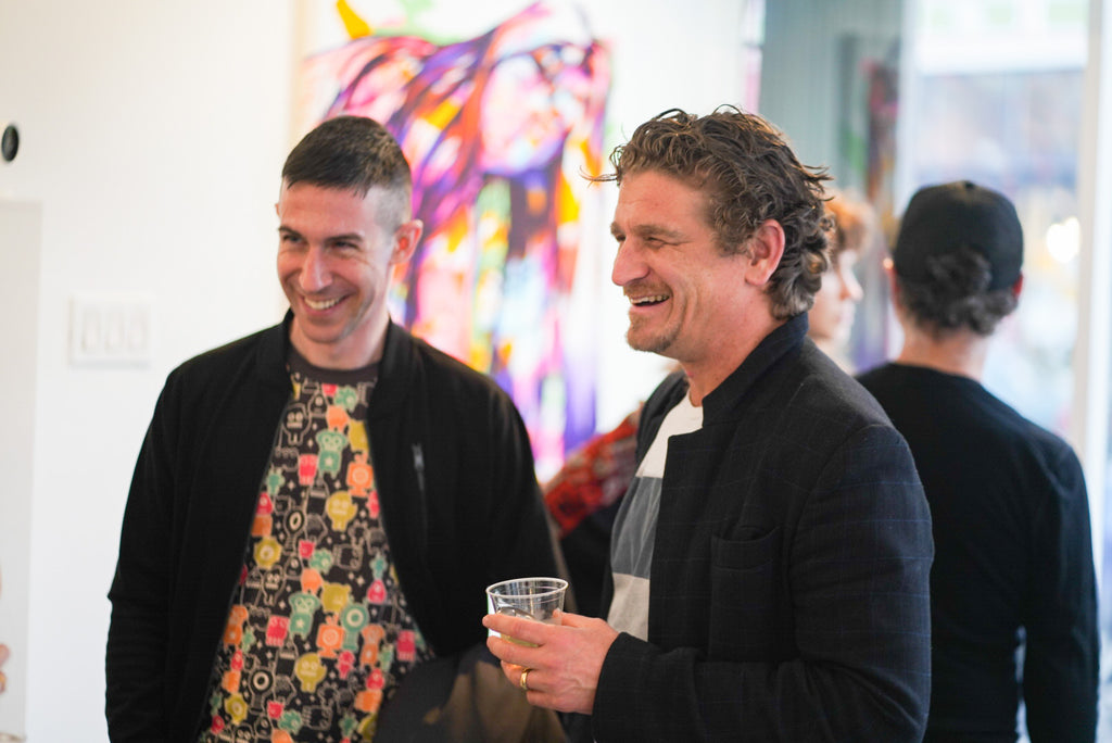 Photograph of two men laughing during The Tracy Piper's Bloom exhibition Opening Reception at Voss Gallery, San Francisco, March 18, 2022.