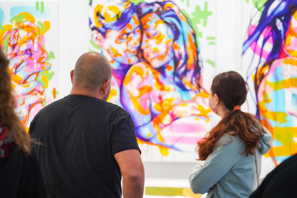 Photograph of two people viewing artwork during The Tracy Piper's Bloom exhibition Opening Reception at Voss Gallery, San Francisco, March 18, 2022.