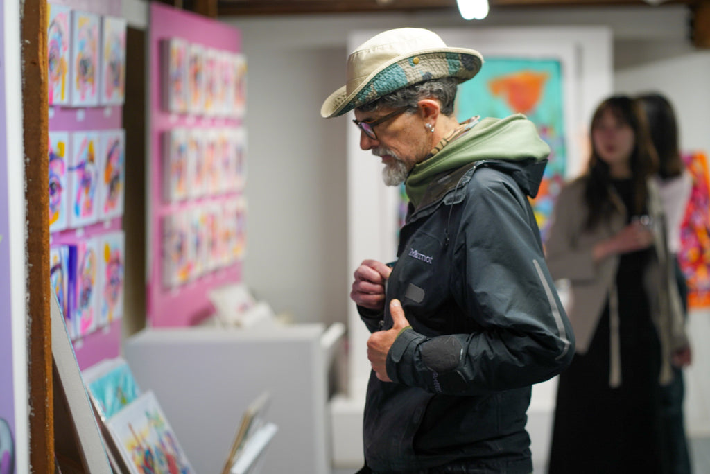 Photograph of an old man viewing eye paintings during The Tracy Piper's SEEN Volume 2 Pop Up Show & Book Signing at Voss Gallery in San Francisco, June 2, 2023.