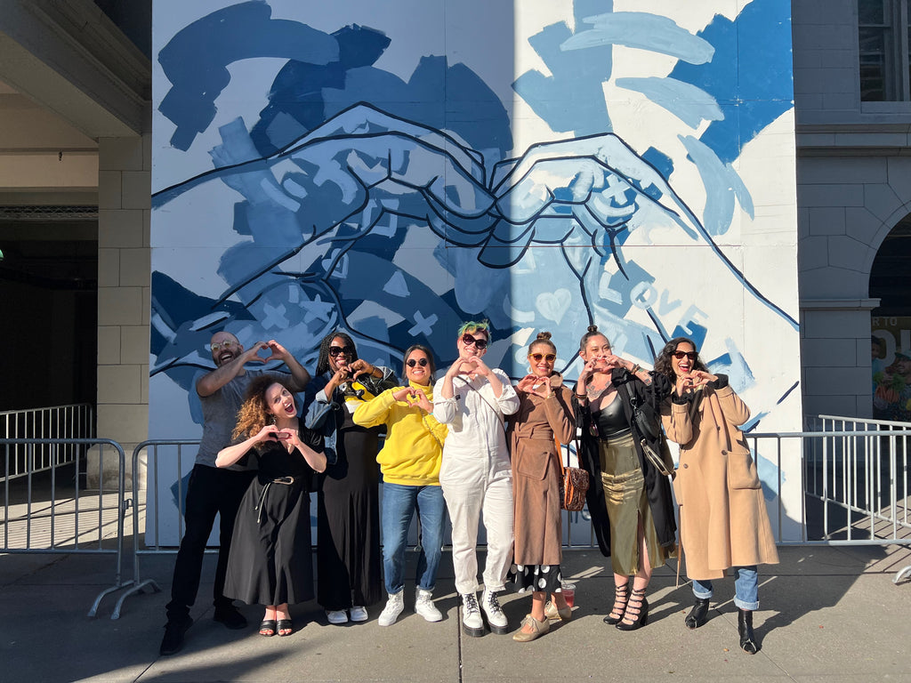 Photograph of The Tracy Piper and Friends in front of the artist's mural at the Ferry Building in San Francisco, 2022.