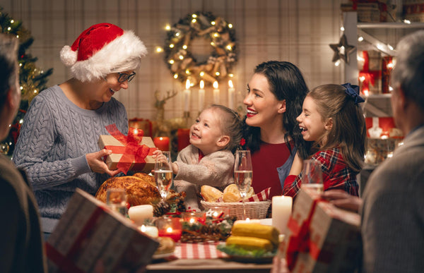 Familia feliz en una cena de Navidad donde le ofrecen un regalo a su abuela.
