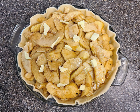 An apple pie with the butter pads before the top crust is put on.