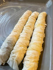 Transfer your baklava rolls of the stick to a buttered pan.