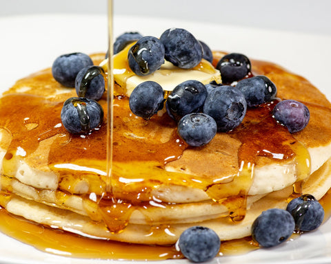 Stack of pancakes with blueberries and maple syrup.