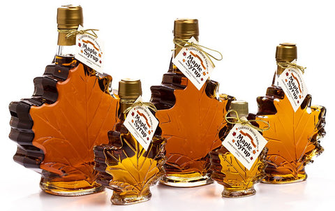 Bottled maple syrup in maple leaf shaped bottles of varying sizes.