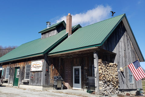 The Carman Brook Farm sugarhouse on a bluebird sky day with steam pouring out from boiling maple syrup.