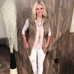 A photo of a bloned woman wearing vest and white pants