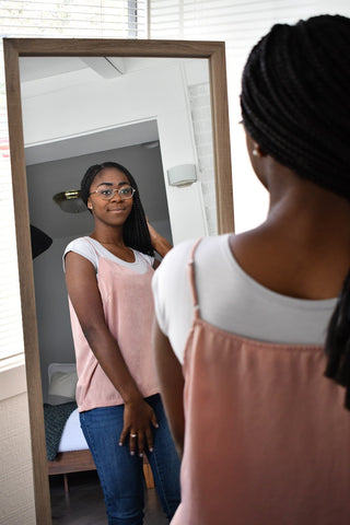 A woman in a pink cap-sleeved shirt admires her reflection in the mirror