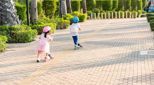 Two children riding skateboards in a park, showcasing their stylish outfits with a trendy layering fashion.