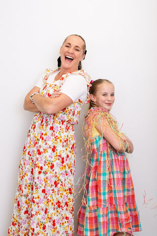 Woman and girl in stylish dresses, smiling for the camera against a vibrant backdrop of spring fashion