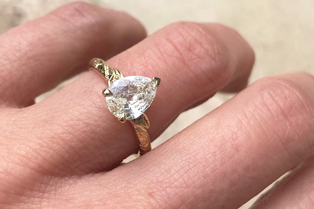 A client's bespoke ethical engagement ring, set with a big pear-shaped recycled old cut diamond in a hand engraved 18ct sustainable recycled gold band