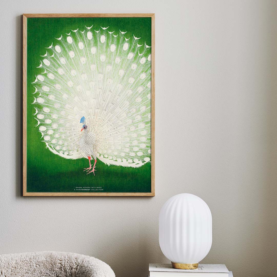 Japansk plakat af en hvid påfugl hænger på en lys væg