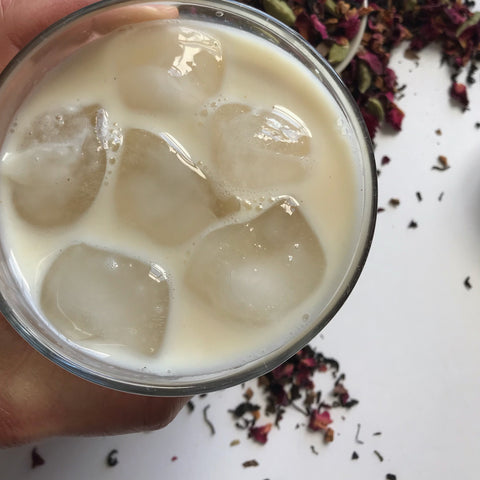 Hand holding a cup of iced Chai, made with a simple steep method. Shanti Chai & Co's Rose Petal Chai, poured over ice. 
