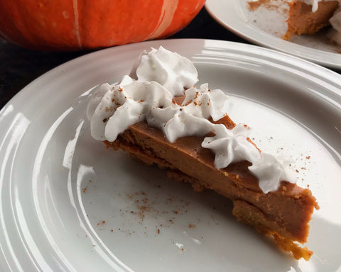 A freshly made piece of Shanti Chai Pumpkin Pie, topped with whipped coconut cream.