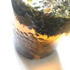 A Mason jar of steeping adaptogenic herbs: ginger, tulsi (holy basil), raspberry leaf and stinging nettle leaf.