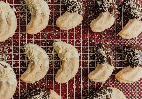 keto macademia nut crescent cookies on a baking rack dipped in chocolate
