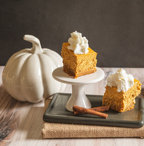 Keto Pumpkin Cheesecake squares on small plates with white ceramic pumpkin