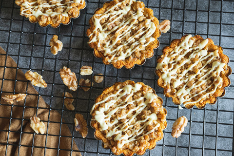 Keto pumpkin praline tarts on a baking rack drizzled with white chocolate