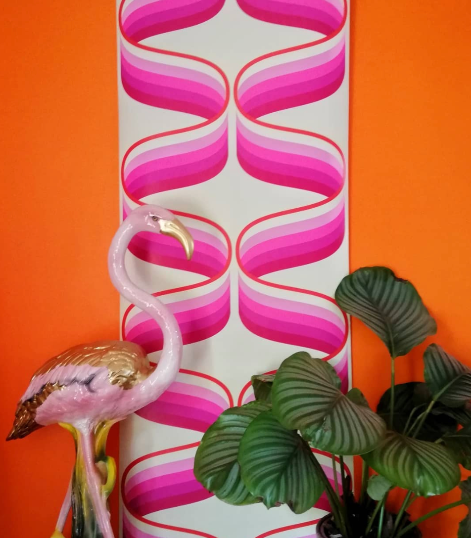 vintage pink and gold flamingo statue in a 70s interior home with 70s wallpaper and plants