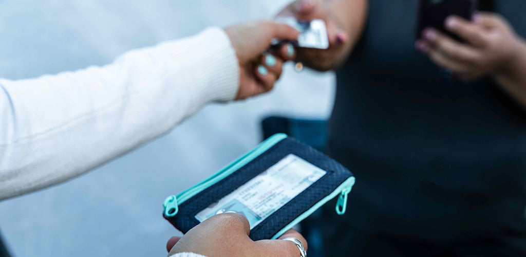 Image shows Chums wallets with RFID-Blocking cards being passed from the hand of one person to another