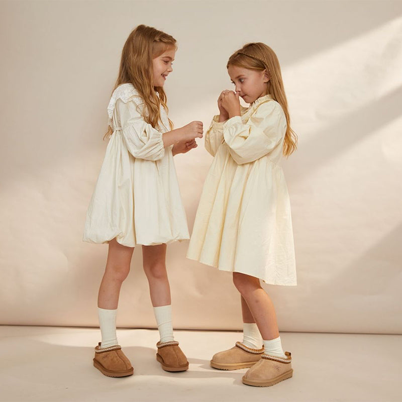 Two kids playing with sheepskin boots on