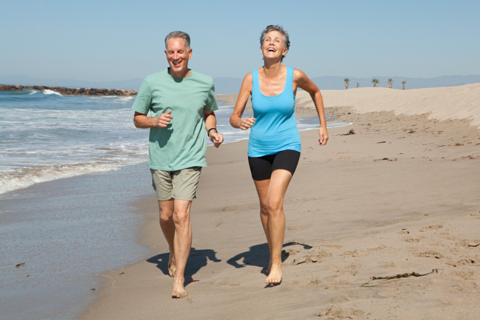sporty senior couple running on beach