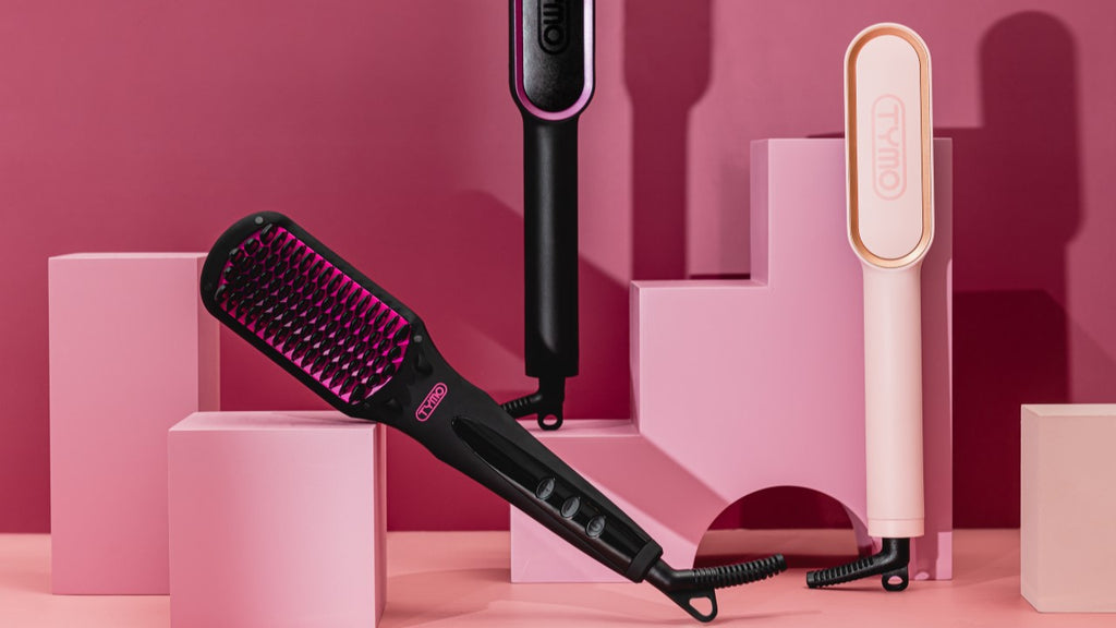 Modern hair straighteners and a brush iron on a pink geometric background, showcasing styling tools for different hair types.
