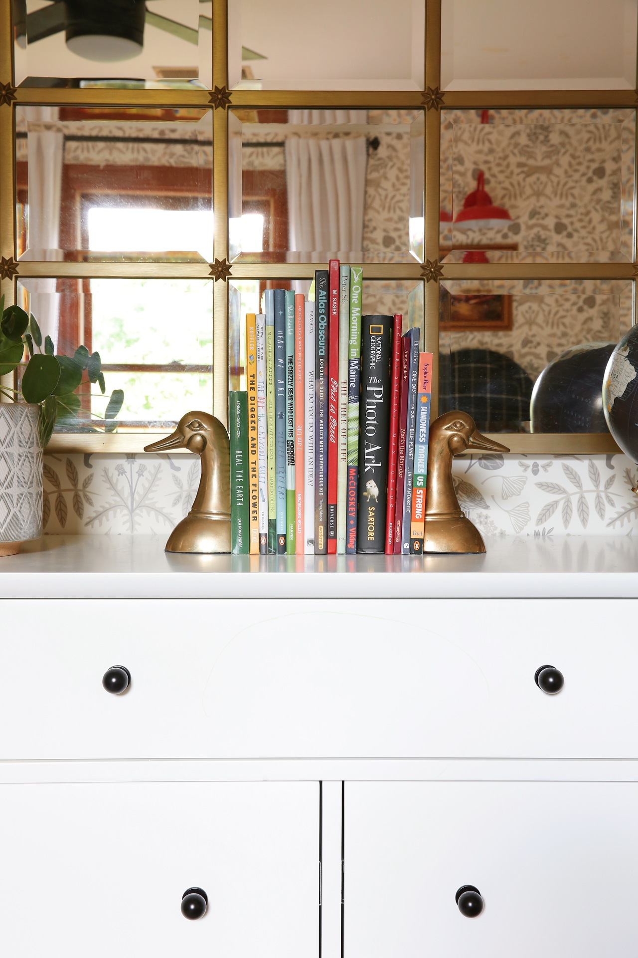 Antique brass duck bookends feel right at home against this wallpaper's nature motif. 