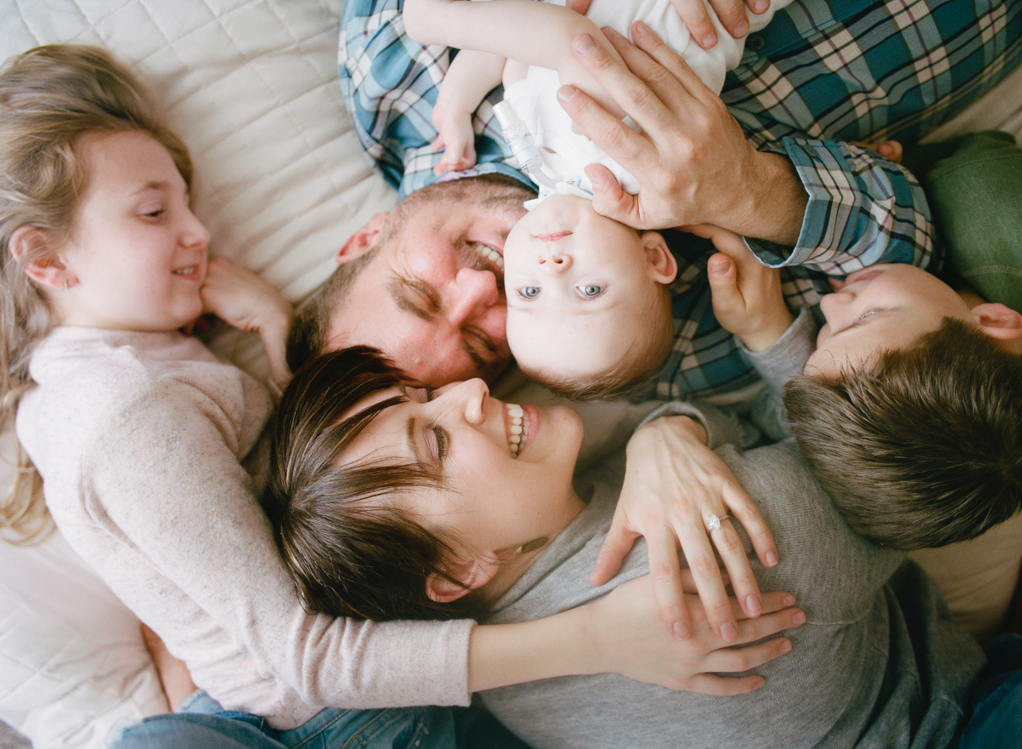Family lifestyle photo of parents and kids hugging and laughing by Kim Hildebrand