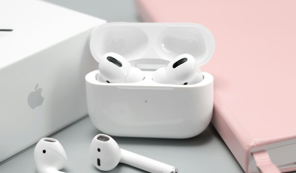 apple airpods case and earphones on a pink background