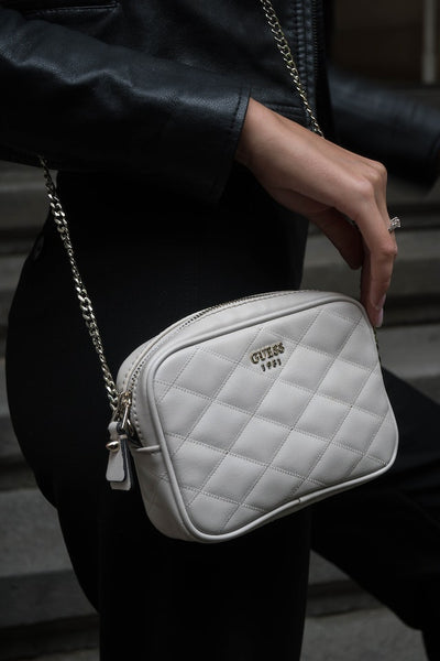 a woman wearing a white Guess bag