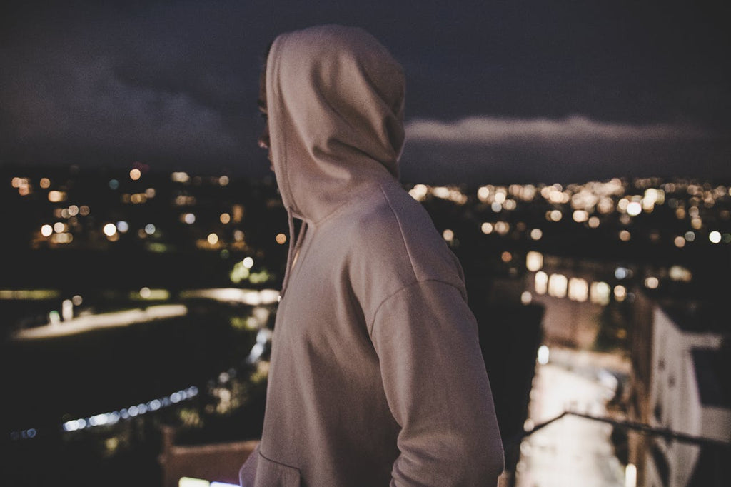 a man in a white hoodie looking at the city at night
