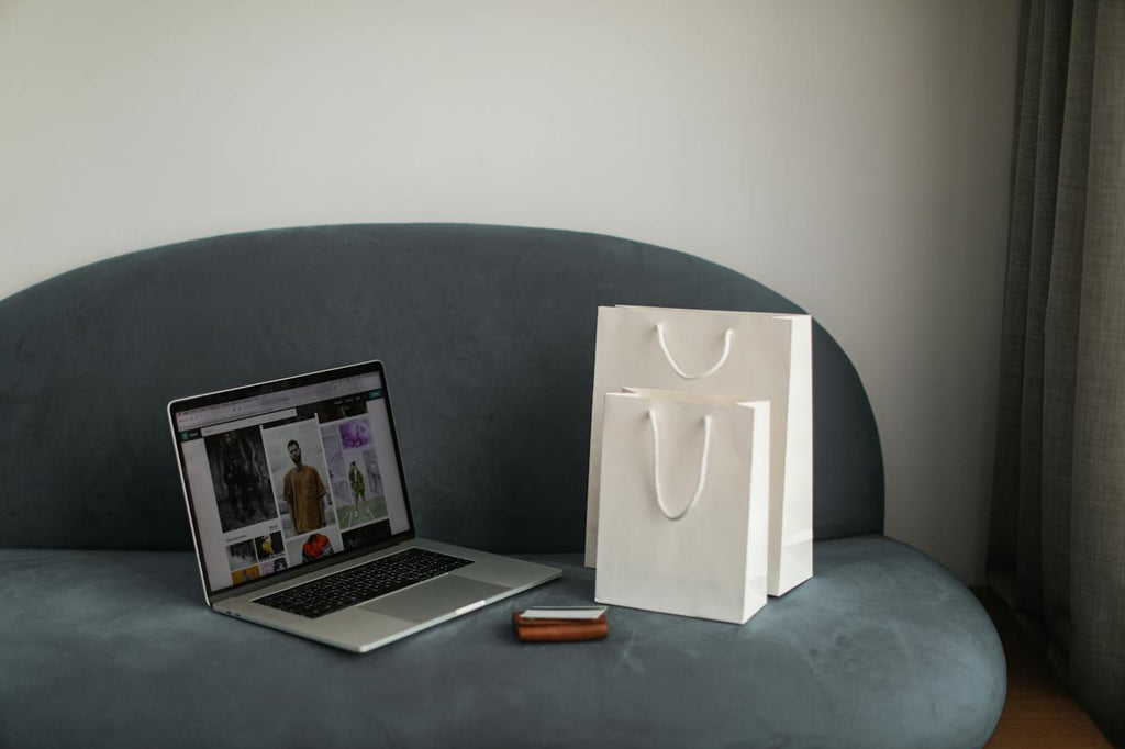 a laptop and shopping bags on a couch