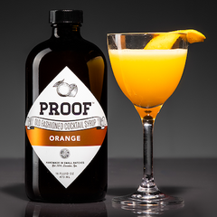 Orange Beach cocktail next to a bottle of Orange Proof Syrup