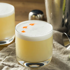 whiskey sour with orange accents sitting on a kitchen table