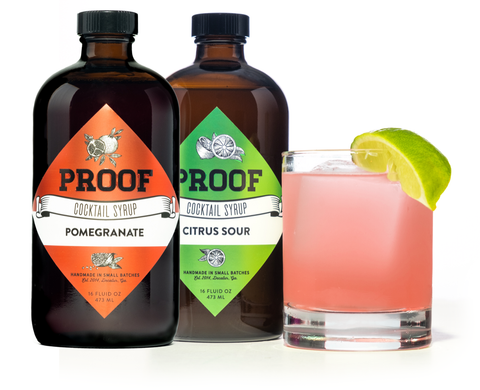 two bottles of Proof Syrup, next to a pomegranate margarita