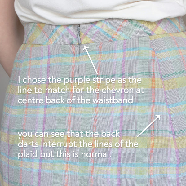 Close-up of Jo's plaid Peppermint Rosalie skirt back waistband. Text reads: I chose the purple stripe as the line to match for the chevron at the centre back of the waistband. You can see the back darts interrupt thelines of the plaid, but this is normal.