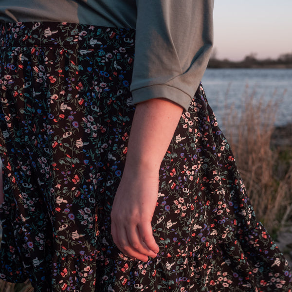 Close up of Bri wearing black floral Forget-me-not Patterns Ella Skirt with flat front elastic back hack